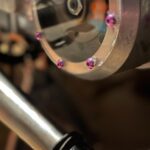 a close up of a metal object with pink flowers on it