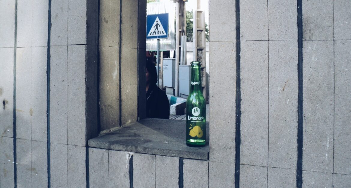 Green bottle on a concrete ledge with street background