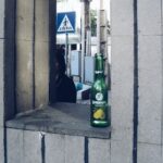 Green bottle on a concrete ledge with street background