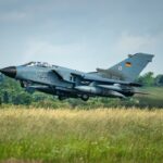 German tornado jet taking off from grassy field.