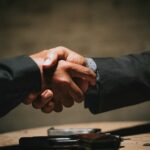 two people shaking hands over a wooden table