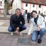 Bürgermeister Steffen Jung und Elena Anesiadis, Sachgebietsleitung Stadtentwicklung, Tourismus, Kultur und Städtepartnerschaft, an einer der neuen Bronzetafeln auf dem Platz der Literatur